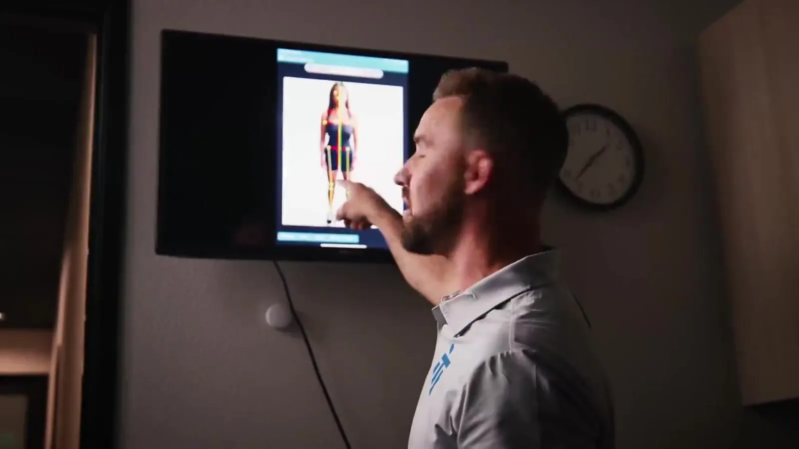 An IMTI clinician walks through a posture screen on a wall monitor
